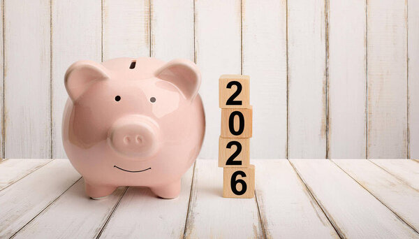 Pink Piggy Bank Next to 2026 Wooden Blocks on White Wooden Floor Representing Savings and Finance Goals