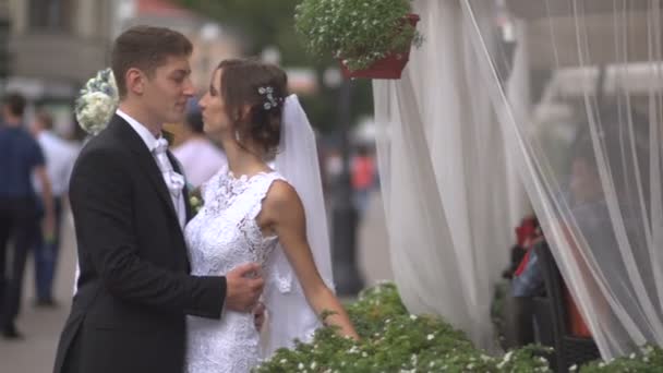 Bride and groom hugging on the street, the bride holding a bouquet — Stock Video