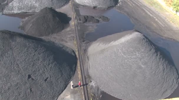 Werknemers lopen tussen stapels van steenkool — Stockvideo