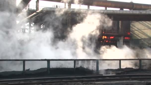 Un coche de paso con un carbón en llamas en el fondo, y el humo en la parte delantera. Producción de coque — Vídeo de stock