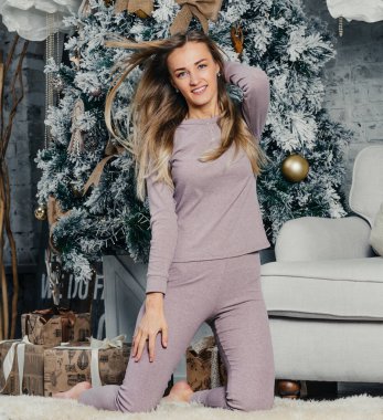 Bej takım elbiseli, uzun saçlı genç ve güzel bir kadın model. Noel ağacı.