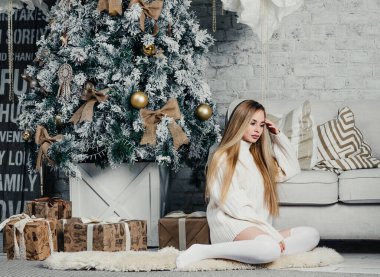 Uzun tozlu uzun saçlı, genç ve güzel bir kadın model. Uzun süveter, Noel ağacı.