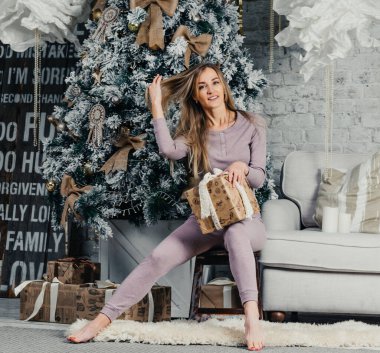 Bej takım elbiseli, uzun saçlı genç ve güzel bir kadın model. Noel ağacı.