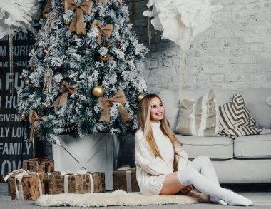 Uzun tozlu uzun saçlı, genç ve güzel bir kadın model. Uzun süveter, Noel ağacı.