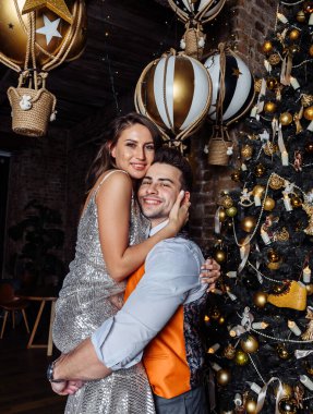 Genç çiftler yeni evliler güler, sevinirler Noel havasına girerler şefkatle sarılırlar, Noel öpücüğünü severler.