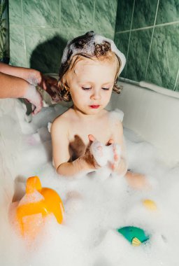 Güzel çocuk çocuk banyo oyunlarında yıkanır sabun köpükleri ve köpüklerle eğlenir.