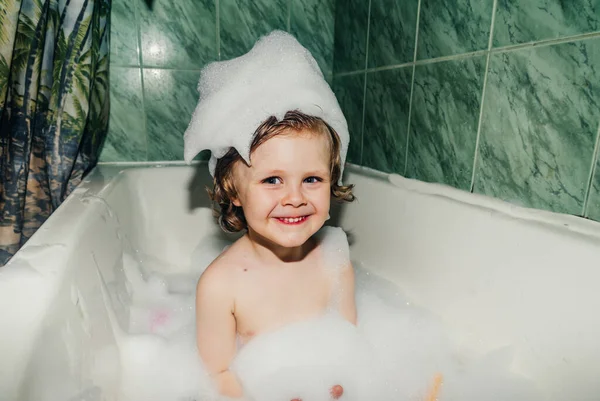 Güzel çocuk çocuk banyo oyunlarında yıkanır sabun köpükleri ve köpüklerle eğlenir.