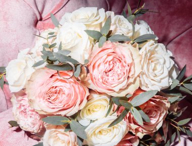 Kutuda beyaz altın alyanslar ve bir buket narin gül ve yeşillik.