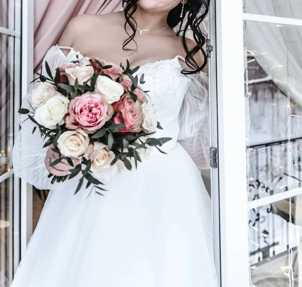 Jeune belle mariée dans une robe de mariée élégante et délicate blanche avec un bouquet de fleurs rose — Photo