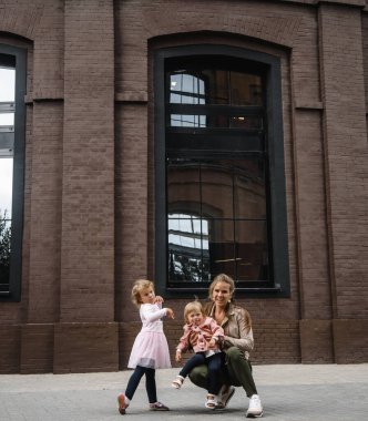 Uzun saçlı, çocuklu, genç ve güzel bir anne. Sokakta yürürken mutluluk, eğlence ve annelik.