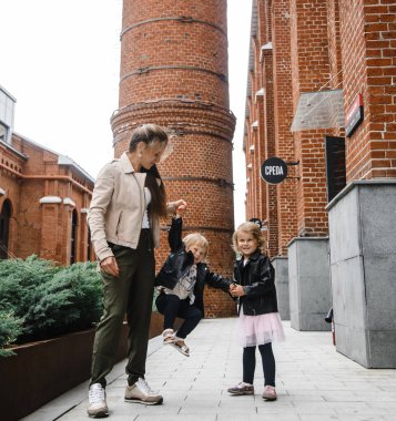 Uzun saçlı, çocuklu, genç ve güzel bir anne. Sokakta yürürken mutluluk, eğlence ve annelik.