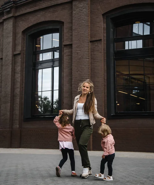 Jeune belle mère aux cheveux longs avec des enfants en promenade dans la rue bonheur joie plaisir maternité — Photo