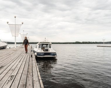 Ufuk nehri kızı deri ceketli ve pantolonlu Sonbahar yürüyüşü iskele botu açık gökyüzü