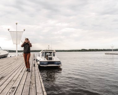 Ufuk nehri kızı deri ceketli ve pantolonlu Sonbahar yürüyüşü iskele botu açık gökyüzü