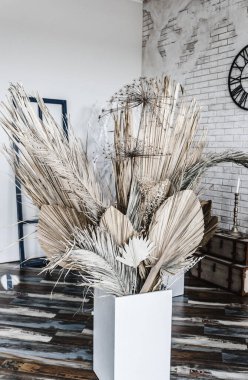 Beyaz bir vazoda, bej kumaş arkaplanda duran kuru ve güzel çiçeklerin süslemeleri. Sınıfta.