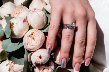 Evlilik yüzükleri takan gençlerin elleri. Düğün günü detayları. Kala çiçekleri. eşler