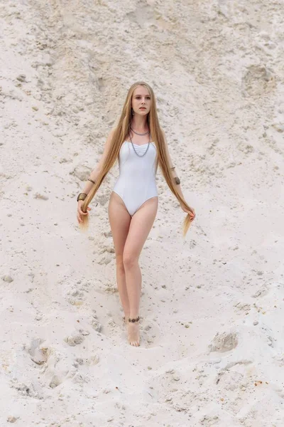 穿着白色泳衣、身材苗条、身材纤细、性感的年轻女子，穿着白色泳衣，躺在沙滩上。 — 图库照片