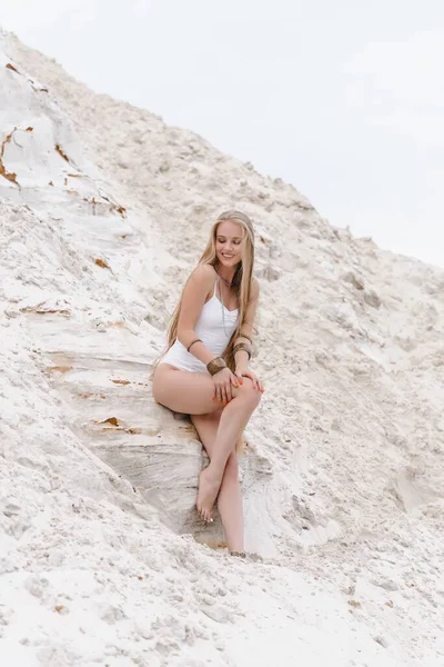 Young slender beautiful slim sexy woman in white swimwear bodysuit on white sand on the beach with — Stock Photo, Image