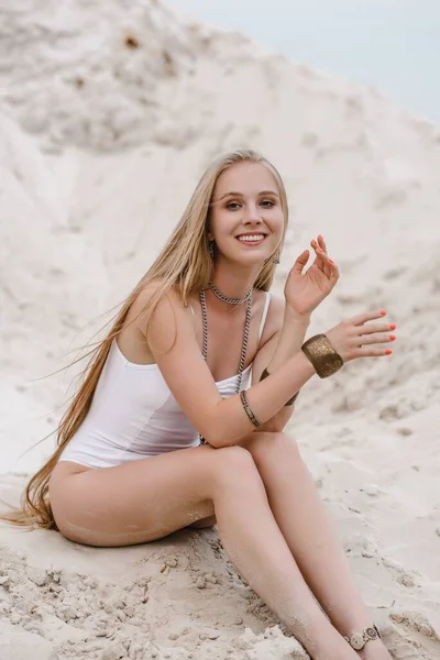 Genç, zayıf, güzel, beyaz mayo giyen seksi kadın kumsalda beyaz bir kumda mayo giyiyor. — Stok fotoğraf
