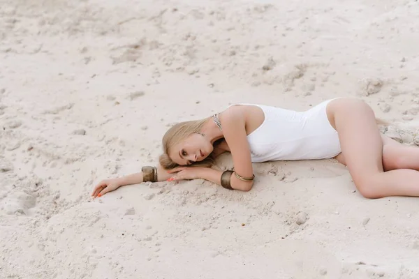 Jong slank mooi slank sexy vrouw in wit badmode bodysuit op wit zand op het strand met — Stockfoto