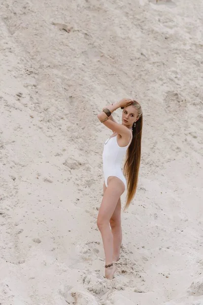 Jovem esbelta bela mulher sexy magro em maiô branco bodysuit na areia branca na praia com — Fotografia de Stock