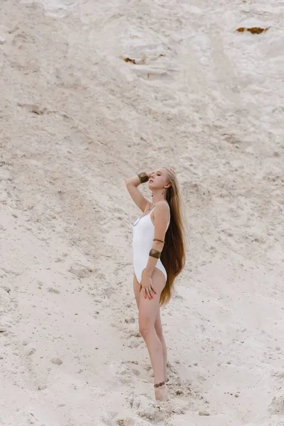 Jong slank mooi slank sexy vrouw in wit badmode bodysuit op wit zand op het strand met — Stockfoto