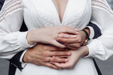 Evlilik yüzükleri takan gençlerin elleri. Düğün günü detayları. Kala çiçekleri. eşler