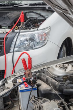 Gün yağmur içinde başka bir binek aracı bir ölü araba pil şarj etmek için bağlantı kablosu kullanarak.