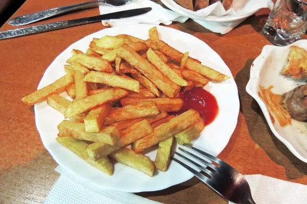 Papas fritas sobre papel de calcar a bordo sobre mesa de madera —  Fotos de Stock