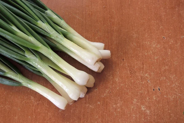 Groene uien op een houten tafel — Stockfoto