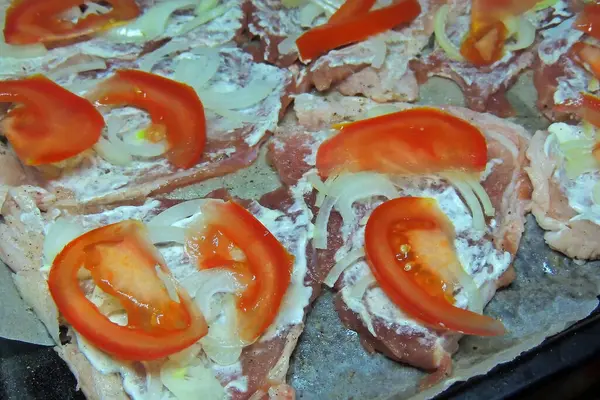 baked pig meat with vegetables and cheese, on a plate, on a white background, isolate