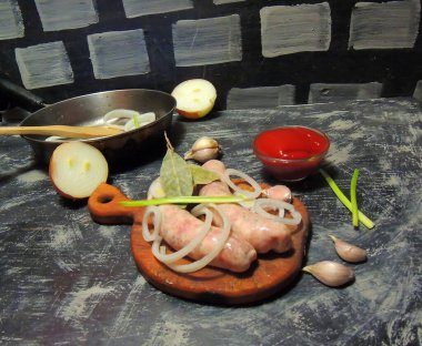 Koyu beton bir arka planda dökme demir tavada çiğ tavuk ya da domuz sosisi..