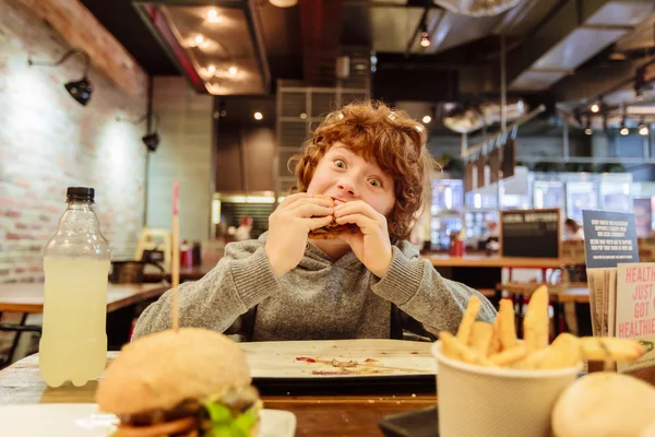 饥饿的男孩在餐厅吃汉堡 — 图库照片