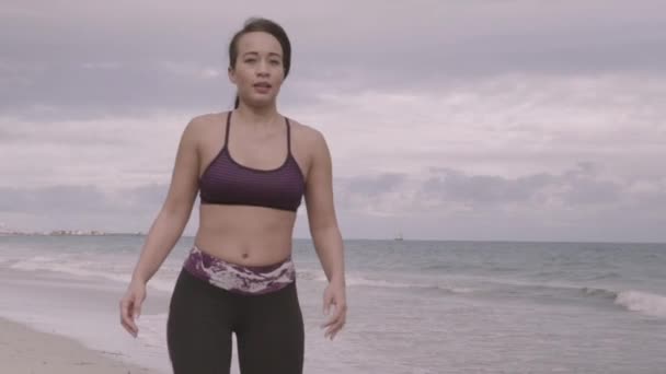 Mujer joven ejercitándose en la playa con el tiempo nublado. Estiramiento. Fitness. Moción lenta — Vídeo de stock