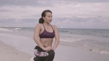 Bulutlu hava plajda çalışan genç kadın. Germe. Fitness. Ağır çekim