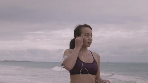 Mujer joven preparándose para trotar en la playa en un clima nublado. Fitness. Moción lenta — Vídeo de stock