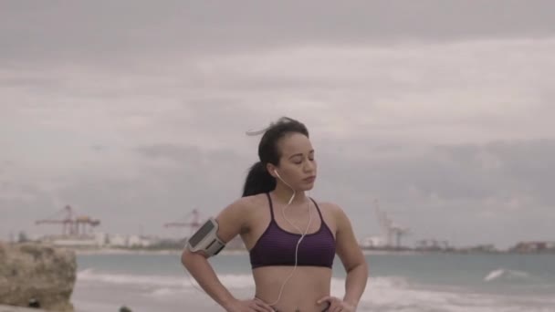 Giovane donna che si prepara per fare jogging sulla spiaggia a tempo nuvoloso. In forma. Rallentatore — Video Stock