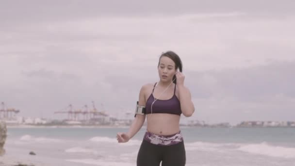 Jonge vrouw voorbereiden joggen op het strand bij bewolkt weer. Fitness. Slow Motion — Stockvideo