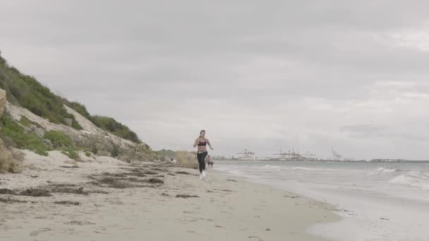 Giovane donna sportiva in forma correre sulla spiaggia. Super lenti colpi stabilizzatore . — Video Stock