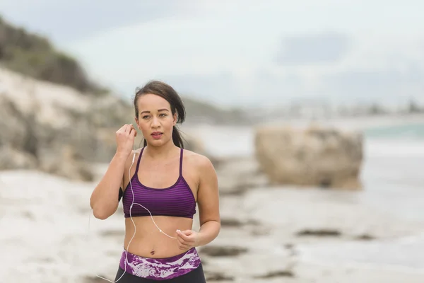 Biegacz przygotowuje się do treningu na świeżym powietrzu na plaży ustawienie słuchawek — Zdjęcie stockowe