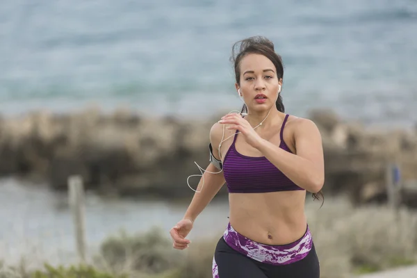 Junge Läuferin joggt an bewölktem Tag am Strand — Stockfoto