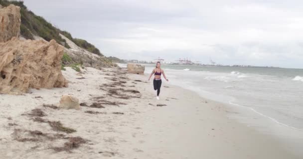 Junge, fitte Sportlerin beim Joggen am Strand. 4k Zeitlupe Stabilisator Schuss. — Stockvideo