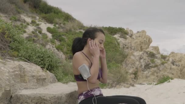 Genç spor kadın egzersiz yaptıktan sonra kumsalda dinlenme yerleştirmek — Stok video
