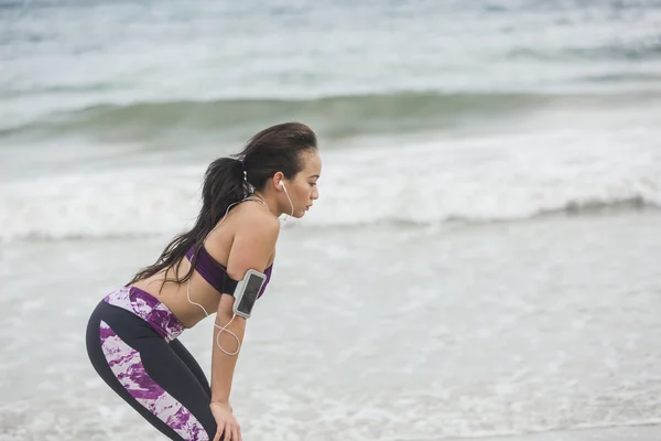 Fitness Mujer descansando después del ejercicio en la playa en el día nublado — Foto de Stock