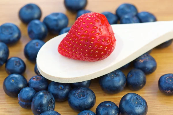 Fragola su un cucchiaio di legno con mirtilli — Foto Stock