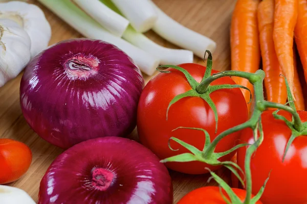 Cebola vermelha e tomate em uma tábua de madeira — Fotografia de Stock