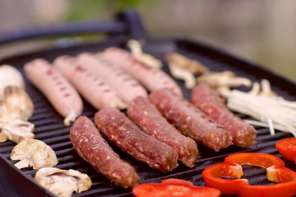 Enchidos e legumes em um churrasco — Fotografia de Stock