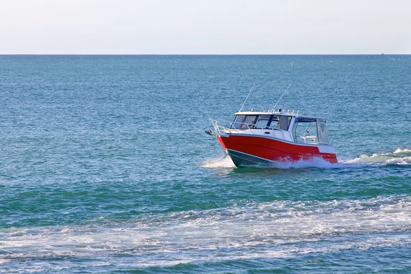 Barco a motor rojo flotando en el océano o el mar — Foto de Stock