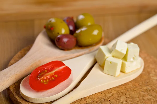 Olives and tomato on a wooden spoons — Stock Photo, Image