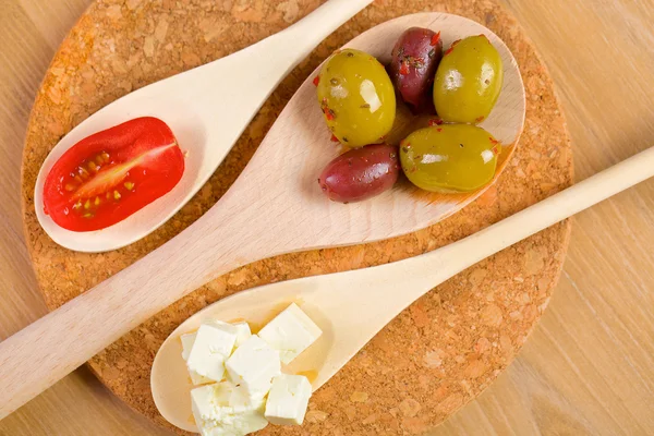 Olives and tomato on a wooden spoons — Stock Photo, Image